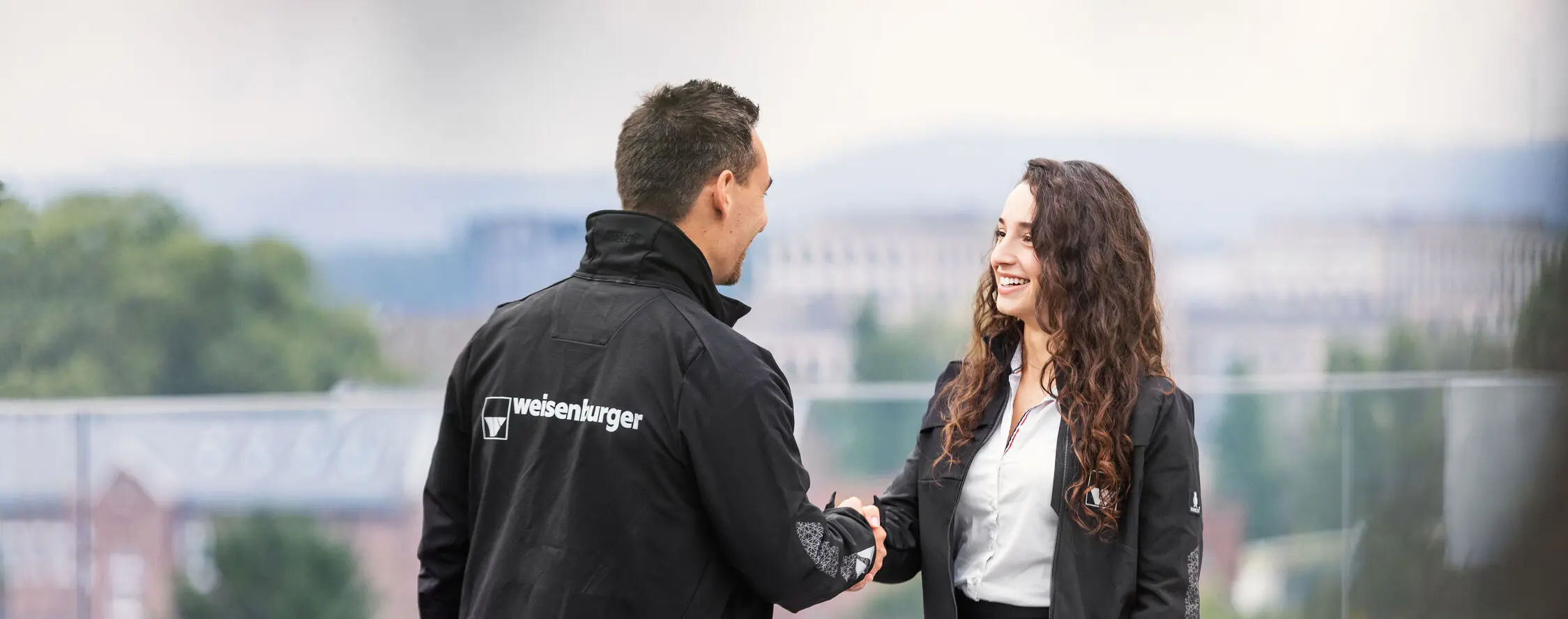 weisenburger-Mitarbeiter-Karlsruhe ein Mann und eine Frau in weisenburger Jacken schuetteln sich gegenseitig die Haende