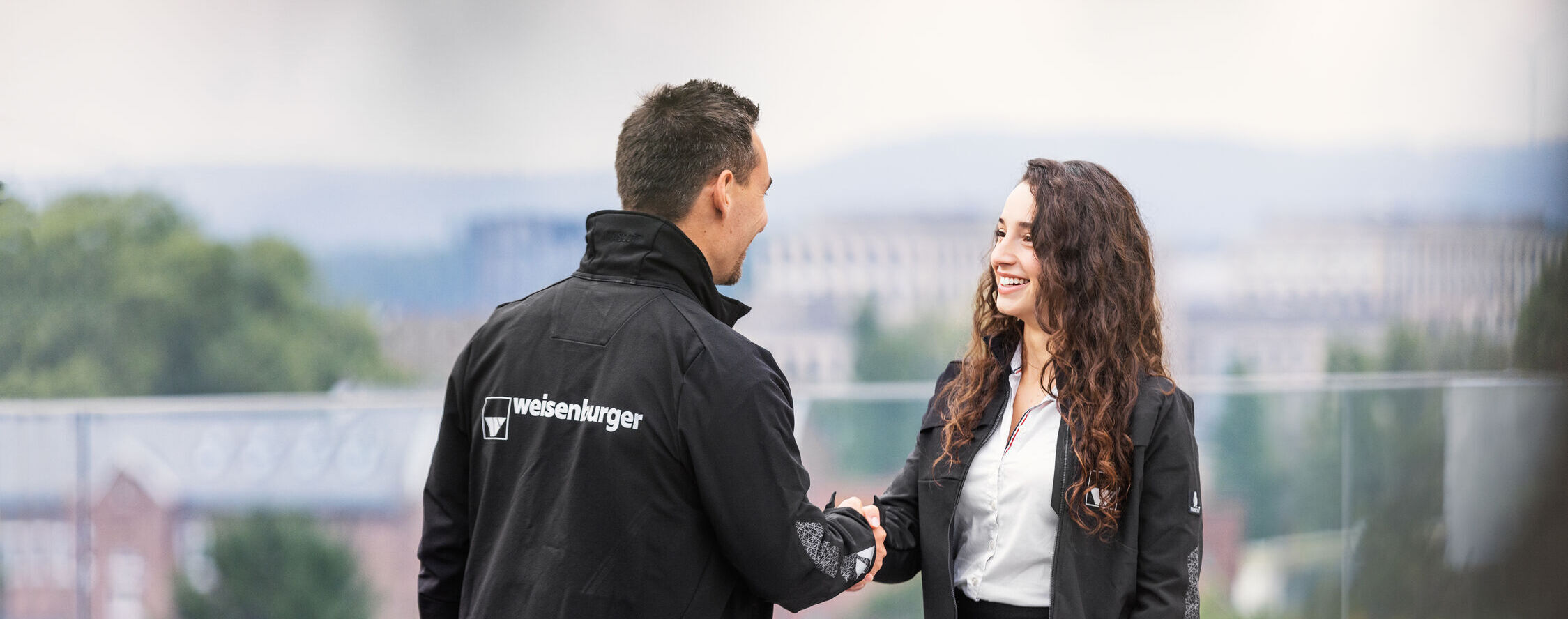 weisenburger-Mitarbeiter-Karlsruhe ein Mann und eine Frau in weisenburger Jacken schuetteln sich gegenseitig die Haende