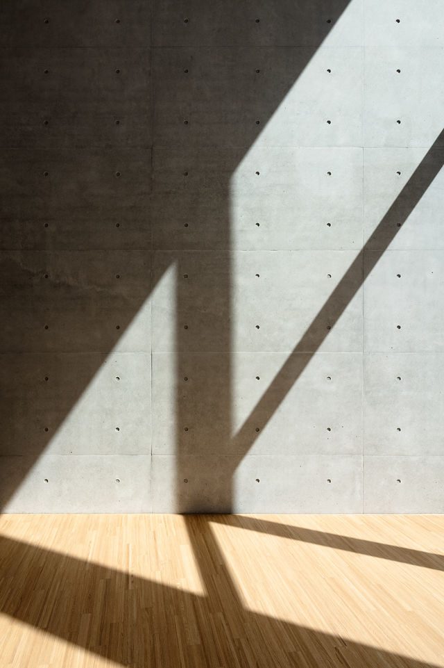 Lichtspiel auf einer Sichtbetonwand und dem Parkettboden im Foyer.