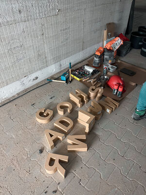 Buchstaben aus Pappe liegen auf einem Steinboden