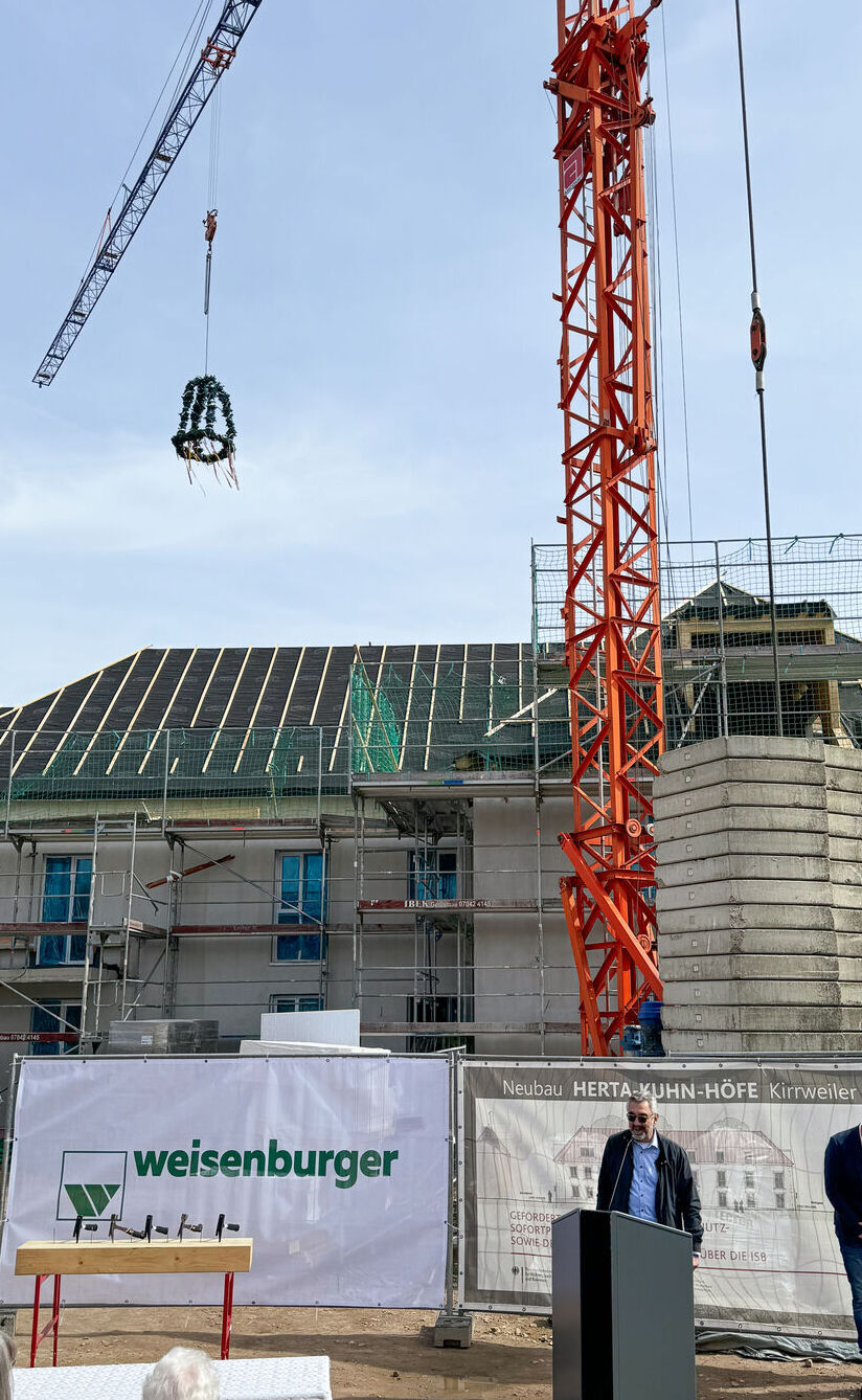 Ein Kran hebt einen Kranz über ein Gebäude welches noch nicht fertig gebaut wurde
