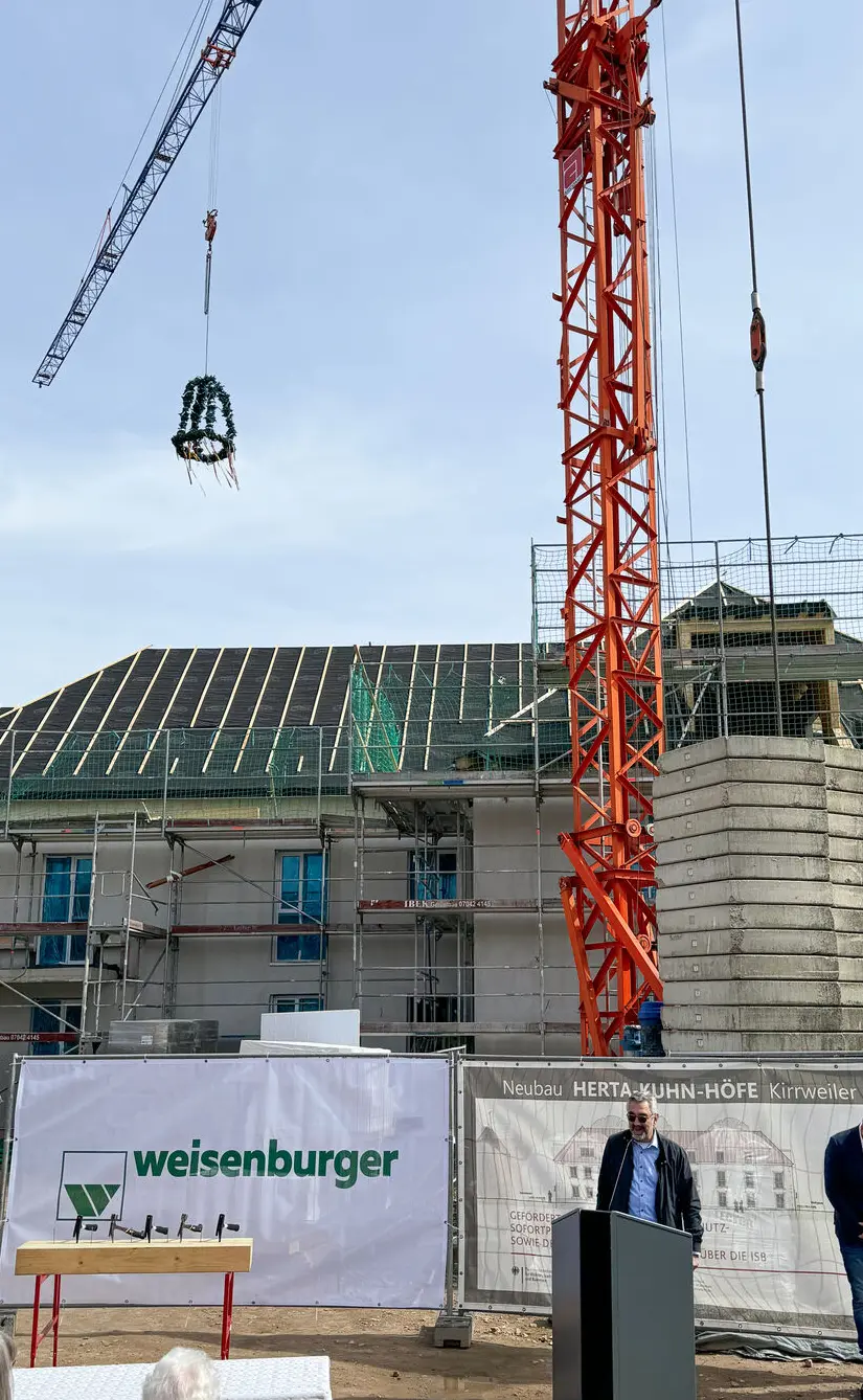 Ein Kran hebt einen Kranz über ein Gebäude welches noch nicht fertig gebaut wurde
