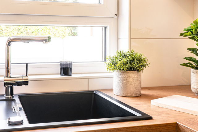 Black built-in sink in front of the kitchen window