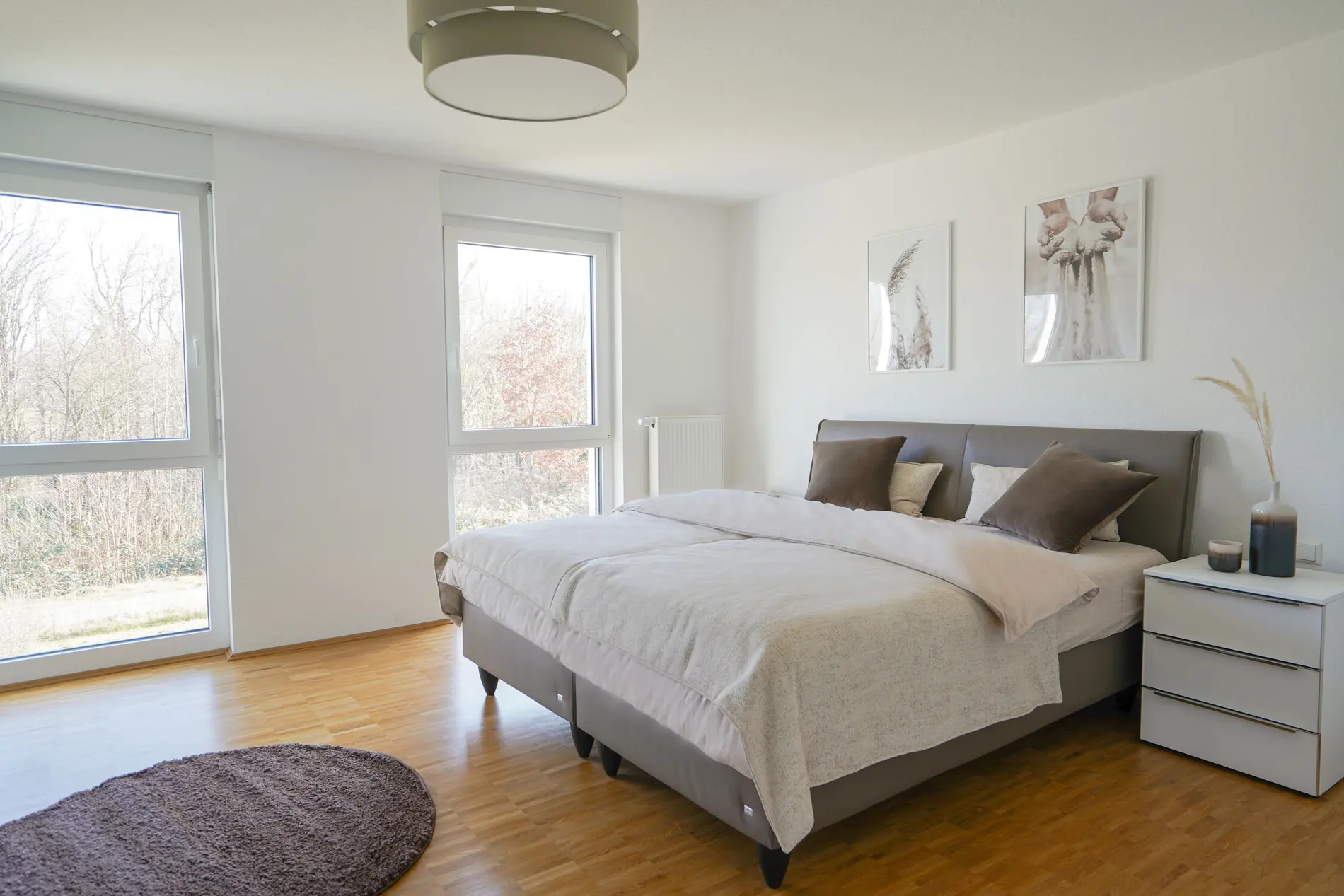 [Translate to English:] Ein Doppelbett mit braunen Kissen und einem Nachtisch