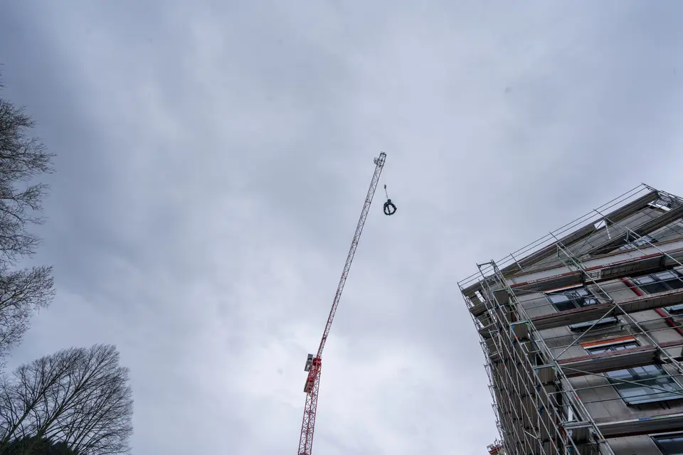 Krahn hebt einen Kranz hoch vor einem Gebäude mit Außengerüst