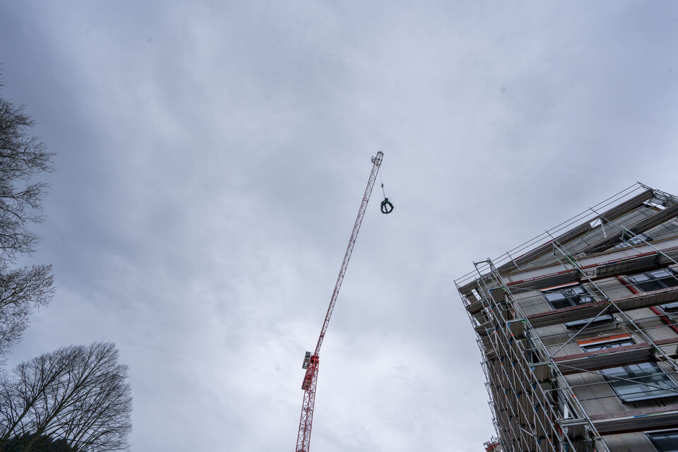 Krahn hebt einen Kranz hoch vor einem Gebäude mit Außengerüst