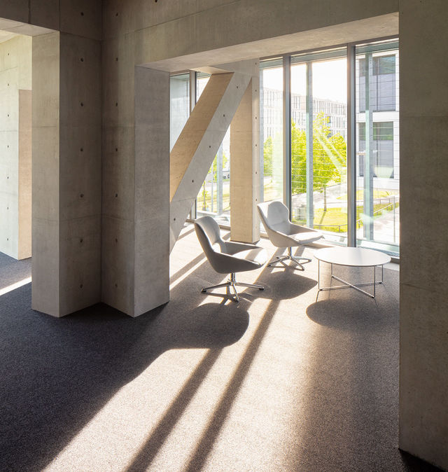 Light falls through the windows onto a cozy seating area surrounded by a truss construction.