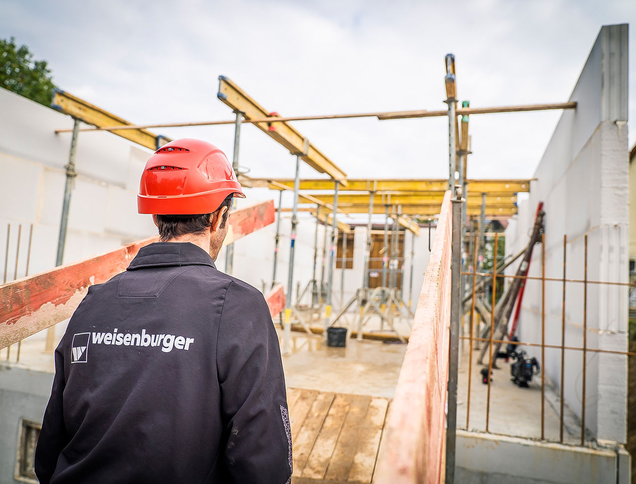 Polier auf der Baustelle Ein weisenburger-Polier mit einem rotem Helm geht zu seiner Baustelle im Rohbau