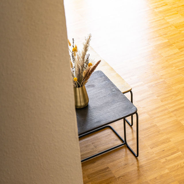 Black side table with dried flowers on wooden parquet