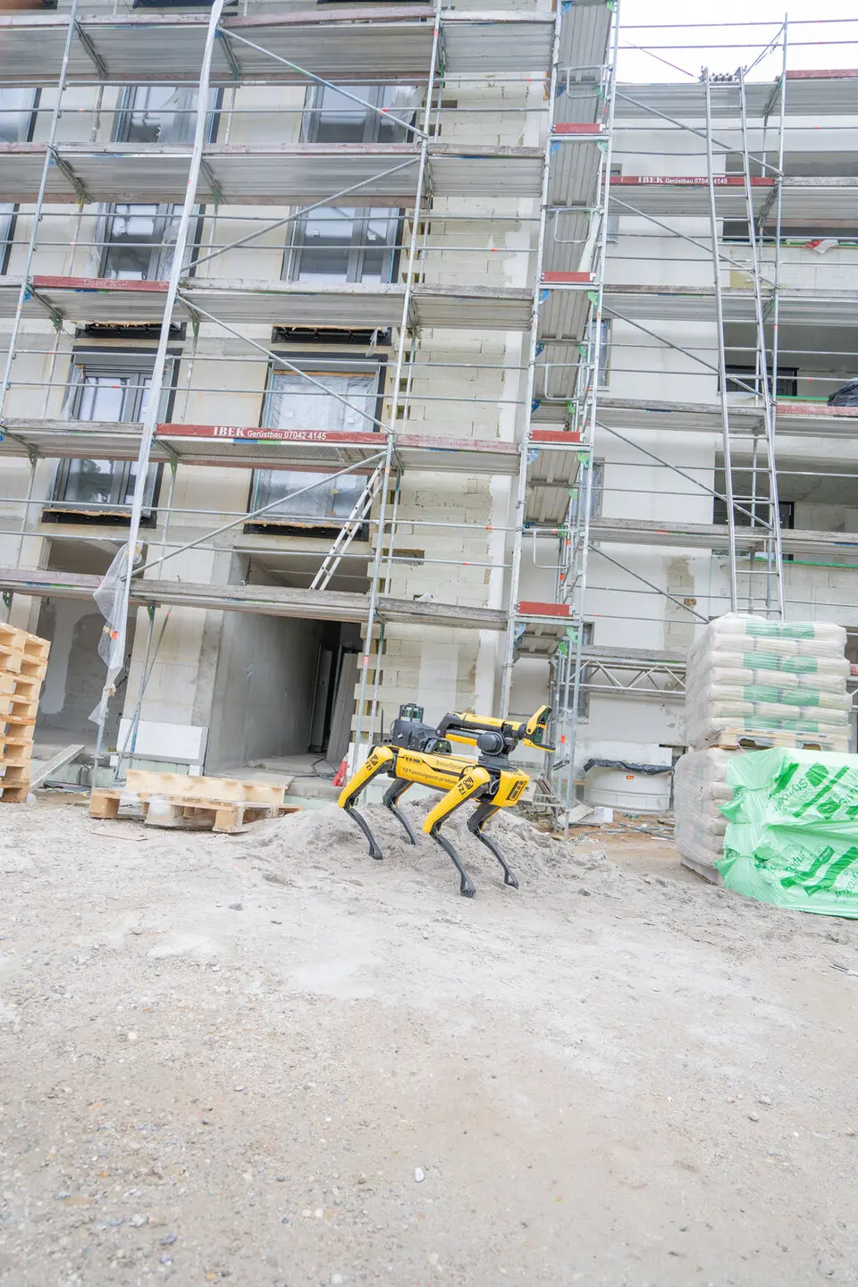 weisenburger Team mit Roboter auf der Baustelle vor einem Gebäude Ein Boston Dynamics Spot Roboter läuft über eine Baustelle vor dem Gebäude