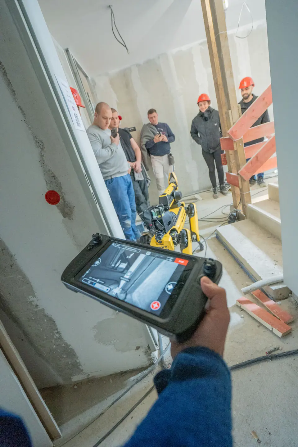 fünf Männer und eine Frau testen einen Robotik in einem Treppenhaus auf einer Baustelle aus