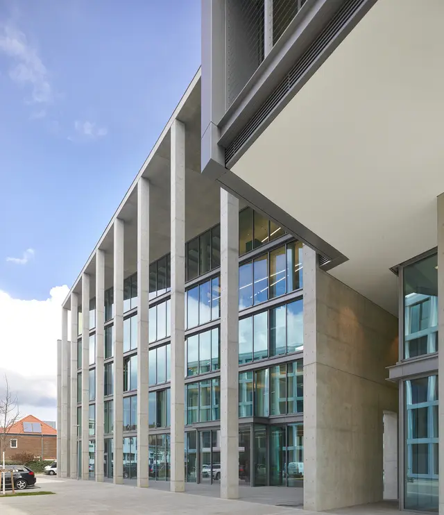 The main entrace of the building on the southwest side is framed by several concrete supports.
