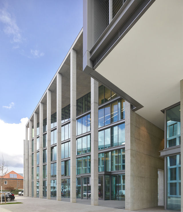 The main entrace of the building on the southwest side is framed by several concrete supports.