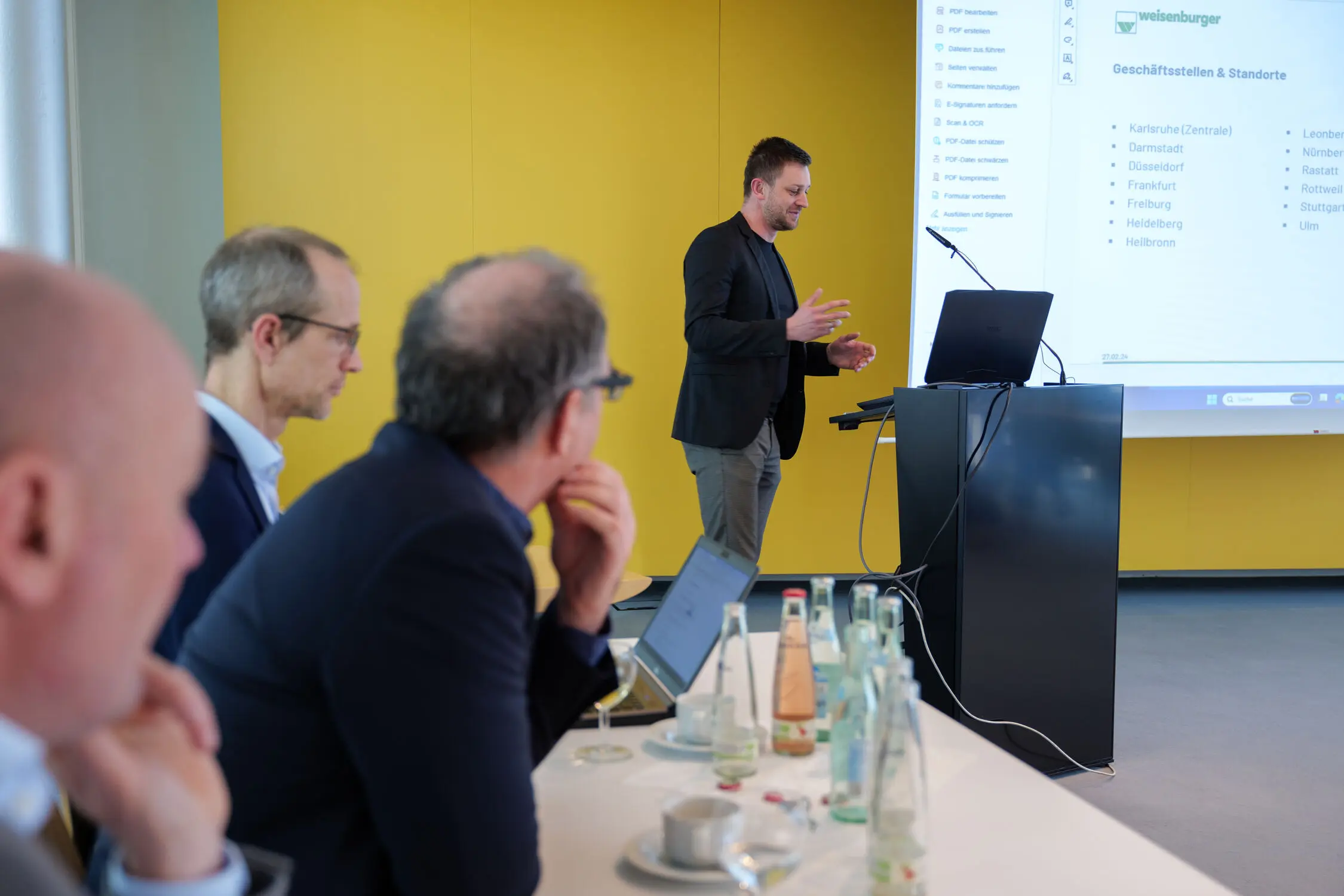 In einem Besprechungsraum wird ein Vortrag von einem Mann gehalten