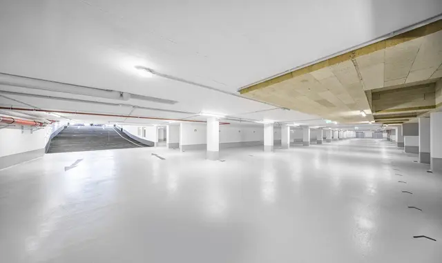 Moderne Tiefgarage mit Rampe Innenansicht einer hellen, beleuchteten Tiefgarage – modernes Design, viele Parkplaetze.