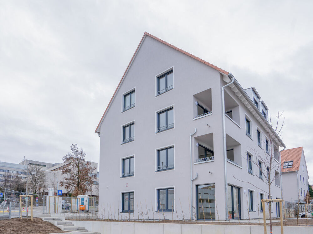 Außenansicht von einem Mehrfamilienhaus, davor steht eine orangene Bank