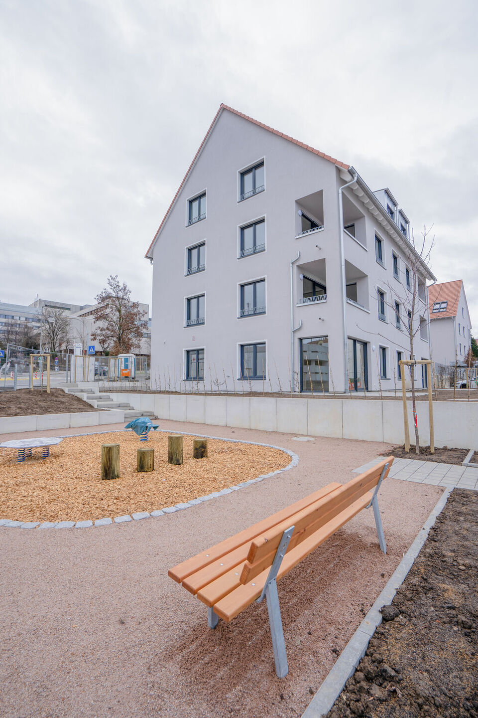 Außenansicht von einem Mehrfamilienhaus, davor steht eine orangene Bank