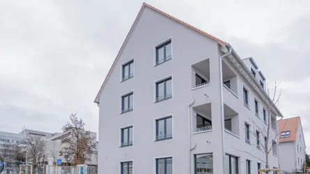 Außenansicht von einem Mehrfamilienhaus, davor steht eine orangene Bank