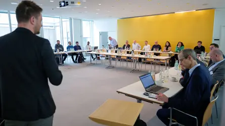 In einem Besprechungsraum wird ein Vortrag von einem Mann gehalten