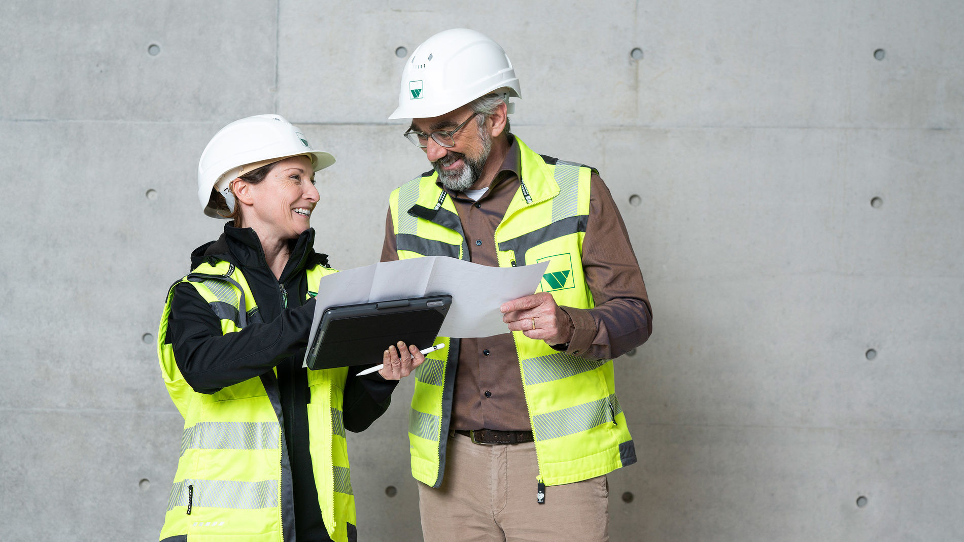 Zwei Mitarbeiter in Baustellenbekleidung besprechen einen Bauplan