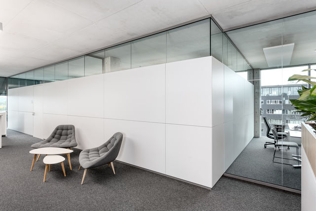 Two comfortable chairs and a table in front of a white partition