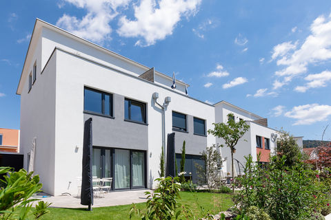 Gartenansicht einer Doppelhaushälfte mit großer Terrasse und zusammengeklappten Sonnenschirmen