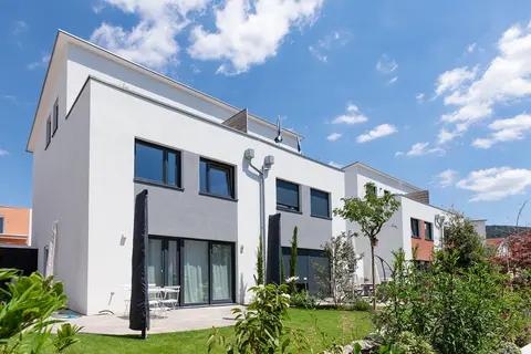 Gartenansicht einer Doppelhaushaelfte mit großer Terrasse und zusammengeklappten Sonnenschirmen
