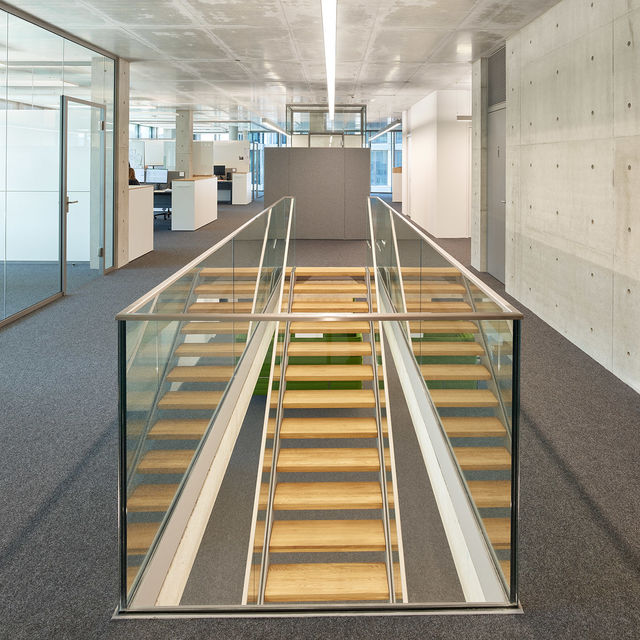 Straight wooden stairs with glass parapets are connecting the floors with each other.