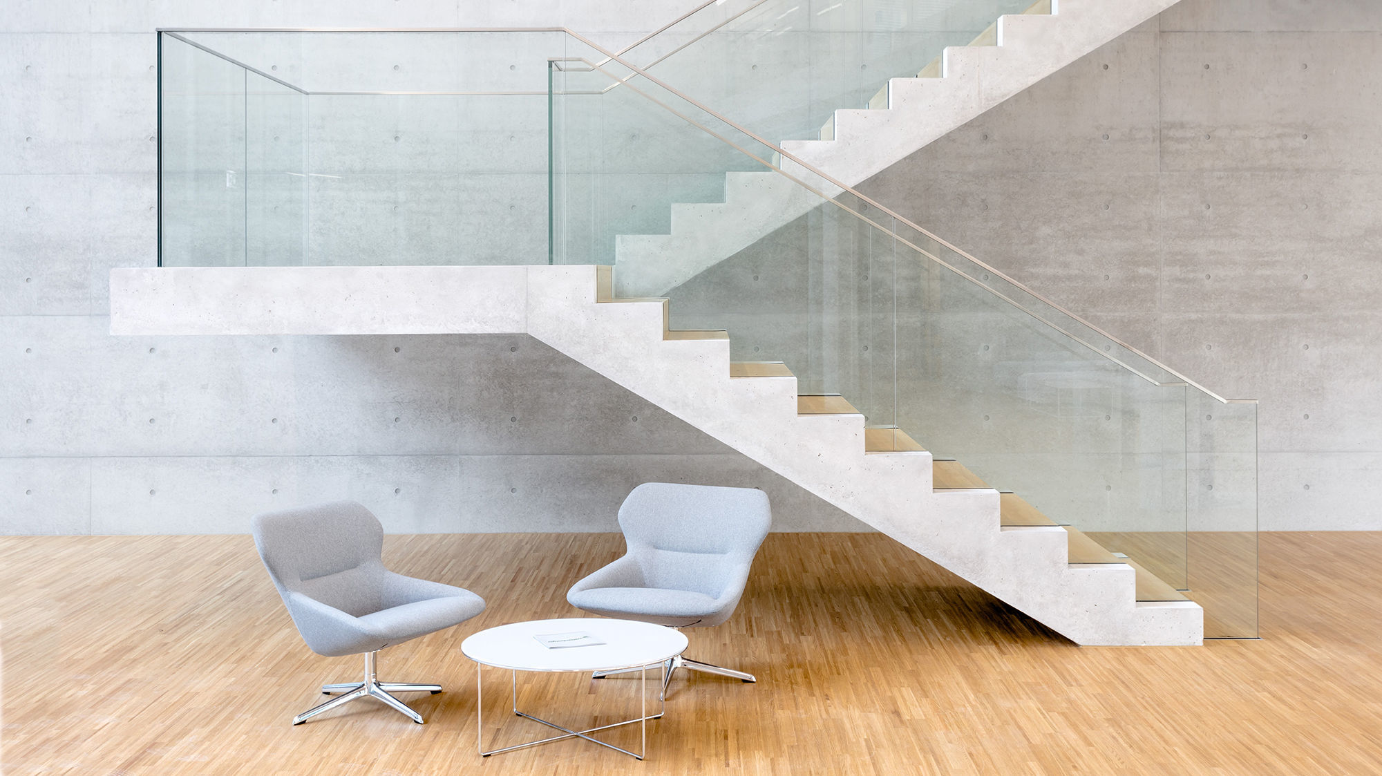 Freitragende Treppe aus Beton mit Glasbrüstung im Foyer der Unternehmenszentrale in Karlsruhe..