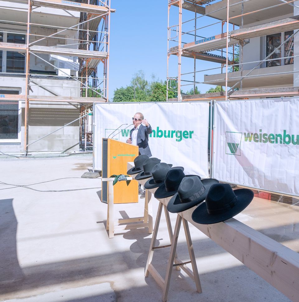 Großbaustelle von mehreren Mehrfamilienhäusern davor stehen Holzstämme mit schwarzen Hüten drauf