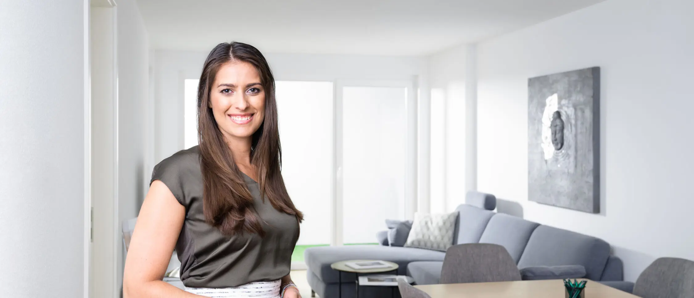 Eine Frau steht in einem Wohn-und Essbereich im weisenburger-Musterhaus und lächelt in die Kamera