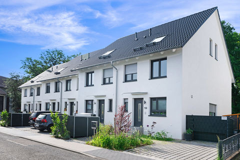 Row of terraced houses painted white with pitched roofs and parking spaces