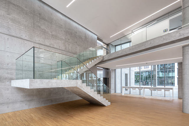 Blick ins Foyer mit frei tragender Betontreppe und Sitzmöglichkeiten