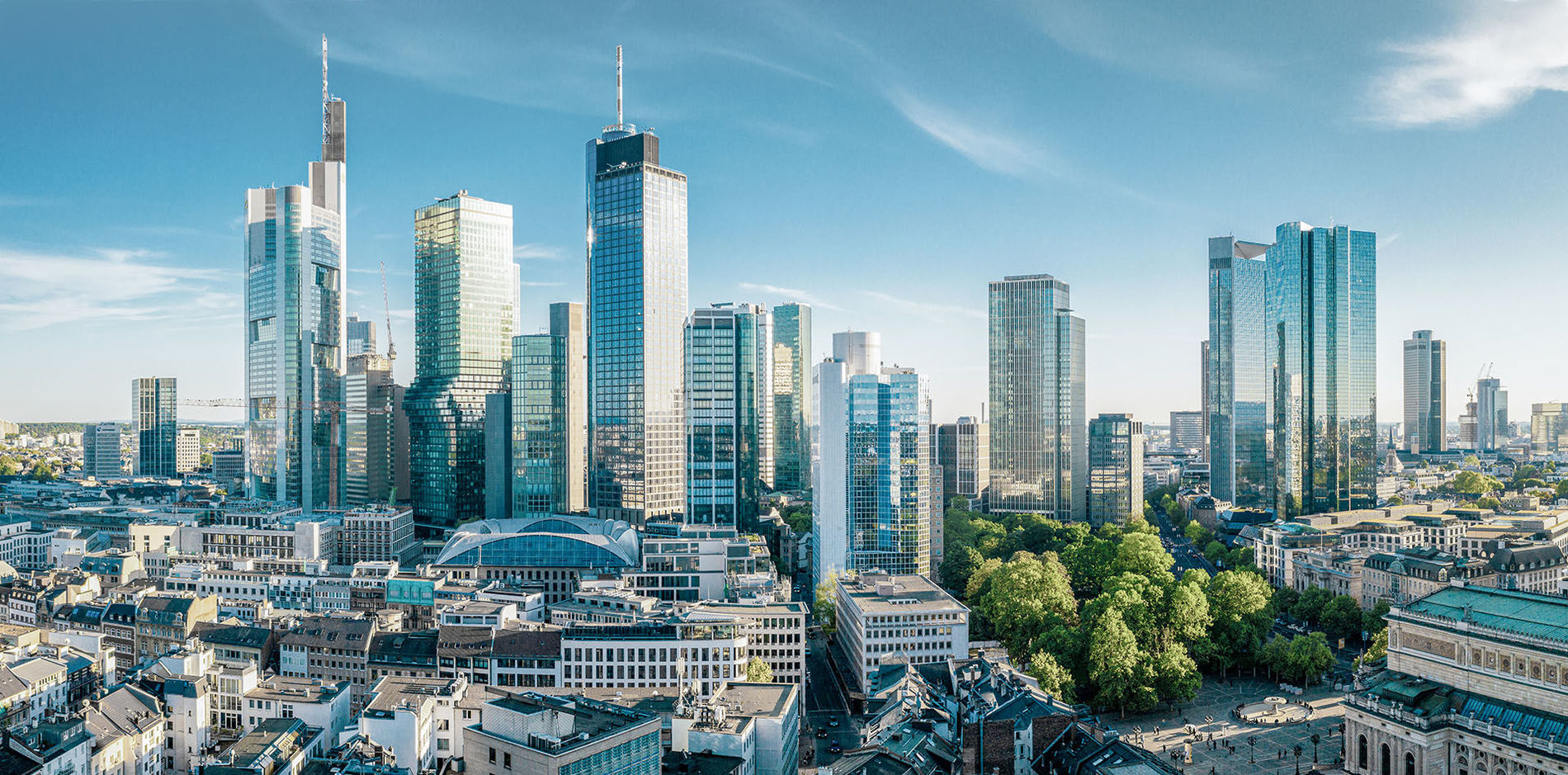Die Skyline Frankfurts mit viele Gebäuden und Hochhäusern vor blauem Himmel 