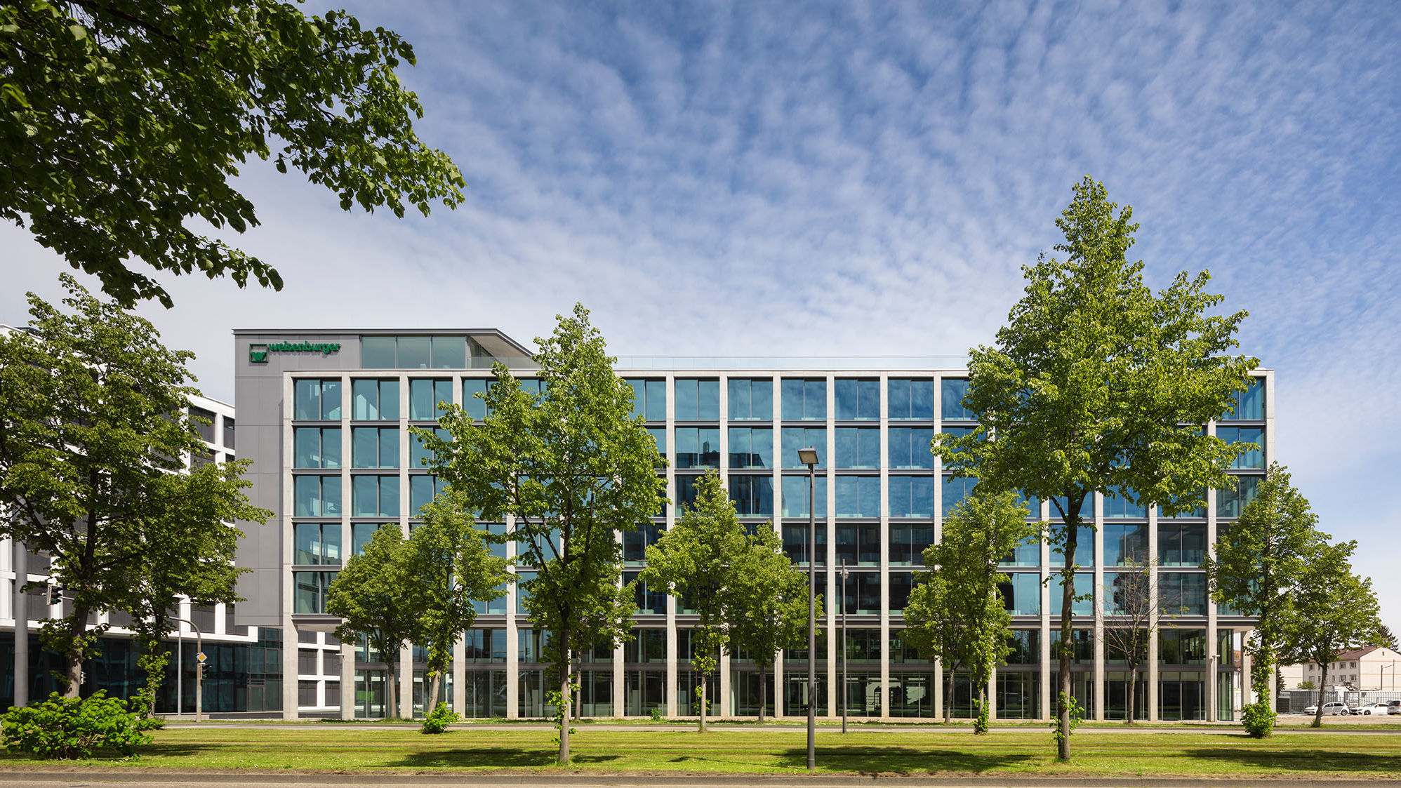 Frontal view of the south facade of the new weisenburger´s headquarter with green trees