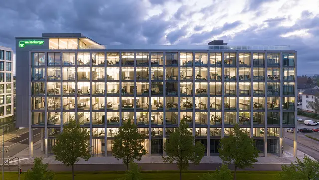 weisenburger-Zentrale in Karlsruhe entworfen von Tadao Ando bei Daemmerung mit beleuchteten Bueros 