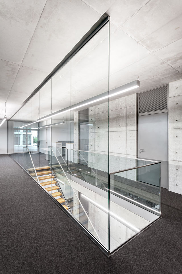 A wooden staircase leads down behind a glass wall