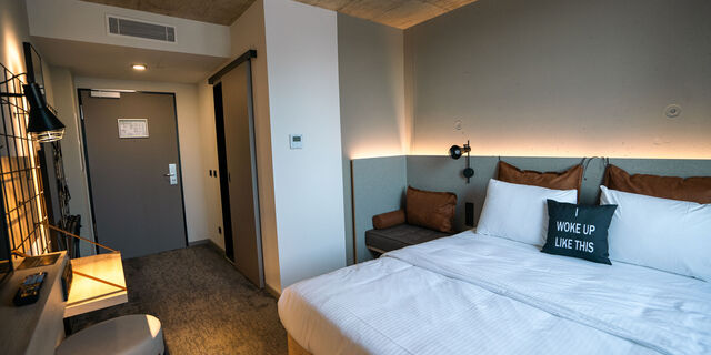 Einrichtung eines Doppelbettzimmer des Moxy Hotel in Karlsruhe mit Bad, Schreibtisch und Garderobe 