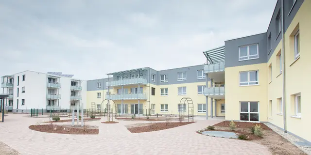 Innenhof der von weisenburger erbauten Pflegeeinrichtung in Iffezheim mit gelber Hausferssade 
