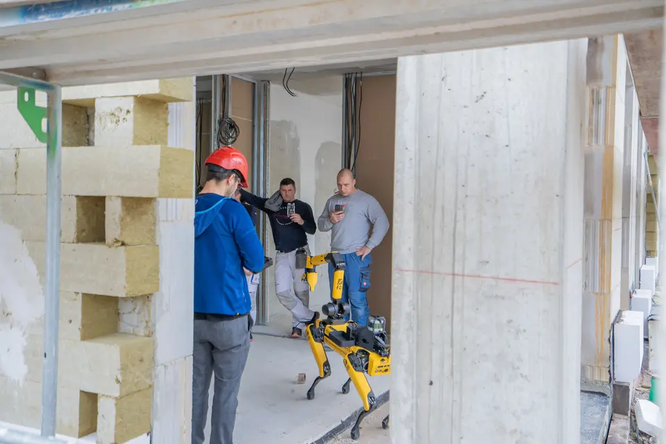 weisenburger Team mit Roboter auf Baustelle Vier Männer testen einen Boston Dynamics Spot Roboter auf einer Baustelle