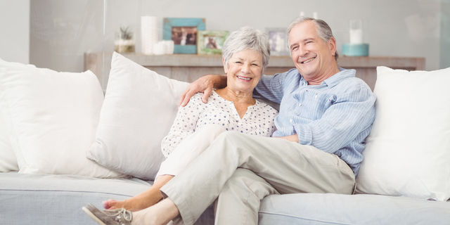 Elderly couple on the couch Elderly couple is sitting on a white couch smiling