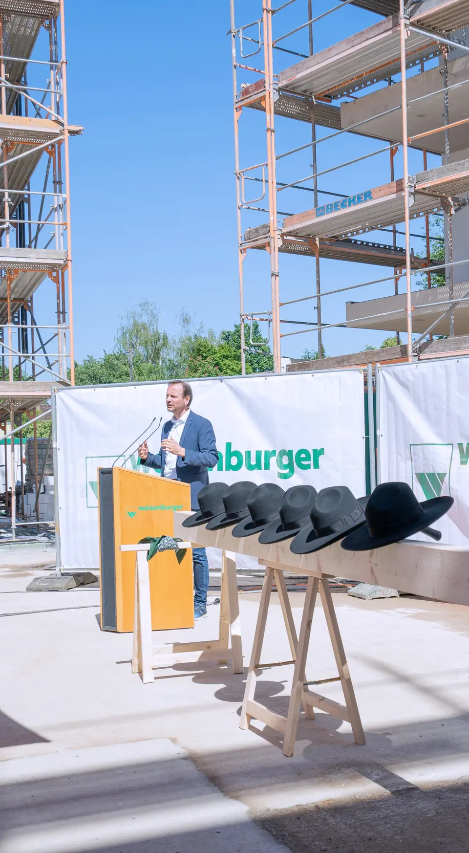 Großbaustelle von mehreren Mehrfamilienhäusern davor stehen Holzstämme mit schwarzen Hüten drauf