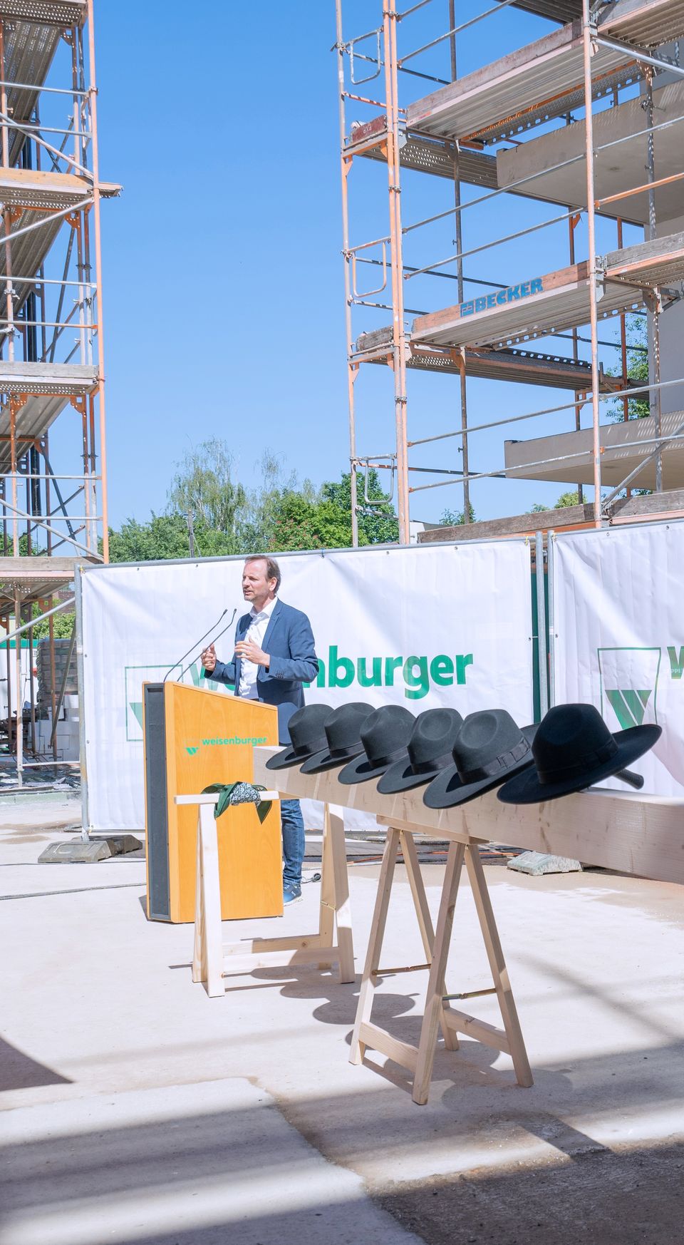Großbaustelle von mehreren Mehrfamilienhäusern davor stehen Holzstämme mit schwarzen Hüten drauf