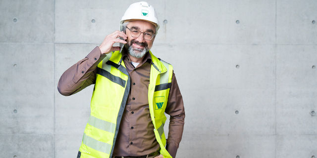 Bauleiter telefoniert Ein weisenburger Bauleiter mit weißem Helm und gelber Warnweste am telefoniert mit seinem Handy