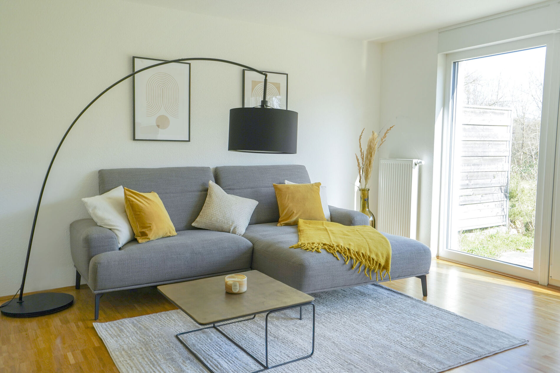 Ein großes graues Sofa mit gelben Kissen mit einem Beistelltisch und einer Stehlampe