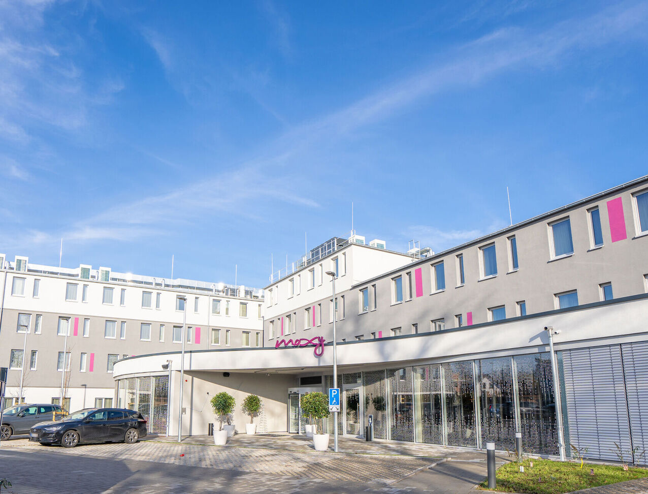 Außenansicht vom Moxy Hotel in Karlsruhe mit Stellplatzen direkt vor der Eingangstuer 