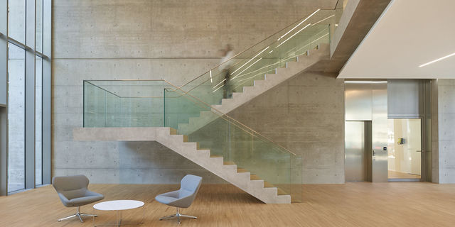 Cantilevered concrete staircase with glass armor in the foyer.