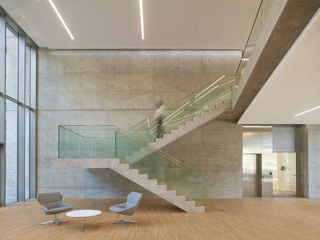 Cantilevered concrete staircase with glass armor in the foyer.