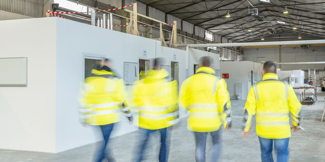 employees of sp24 Four construction managers with yellow jackets on the way to the construction project