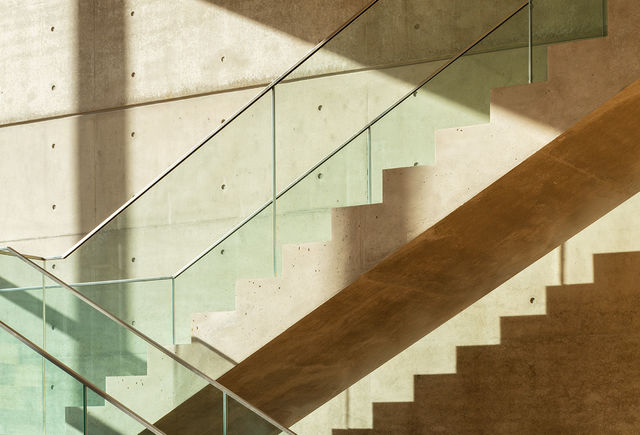 The cantilever concrete staircase in the foyer is lighted by sunlight and casts shadows.